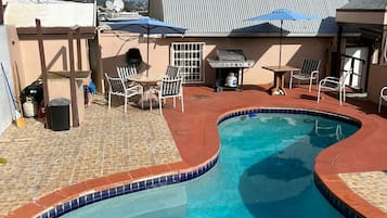 Relax by the pool surrounded by a deck with a unique pattern, lounge chairs, and a barbecue grill.