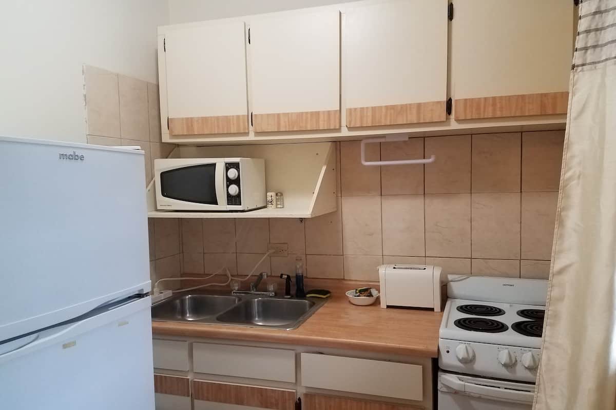 A compact kitchen with a built-in microwave, a toaster, and a stove.