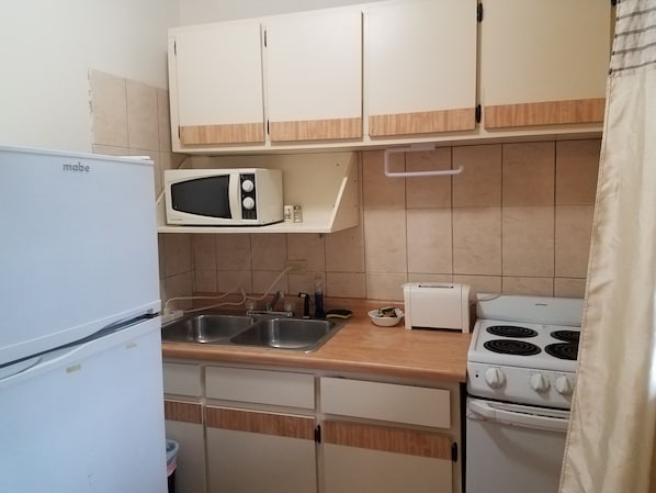 Una cocina compacta con microondas integrado, tostadora y estufa.
