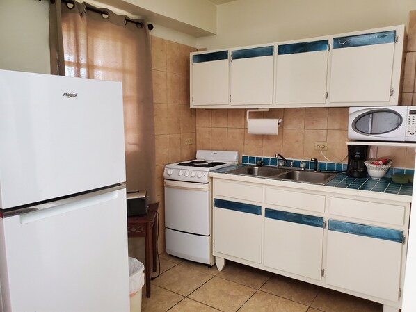 Una cocina compacta equipada con refrigerador, estufa, microondas y pileta.