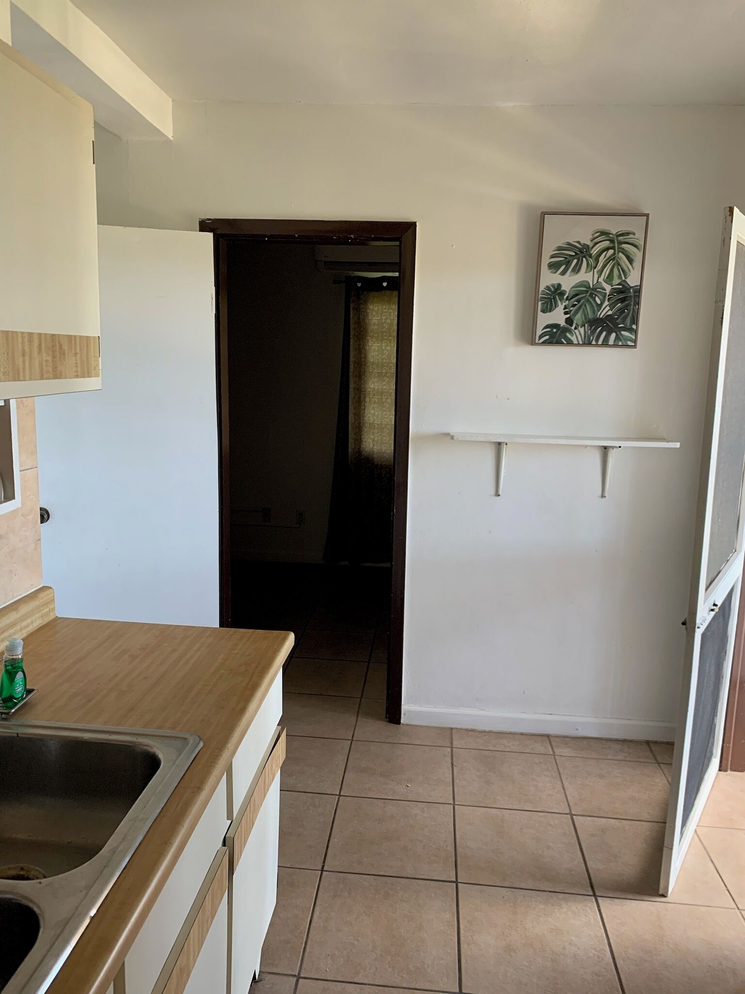 Una cocina con encimera de madera, un lavabo y una puerta que da a otra habitación.