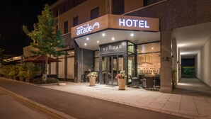 A hotel with a modern facade, a visible bar area, and outdoor seating. - Hotel Arcade (Sins)