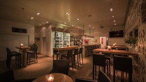 A modern bar area with multiple seating options, a well-lit interior, and a variety of bar stools. - Hotel Arcade (Sins)