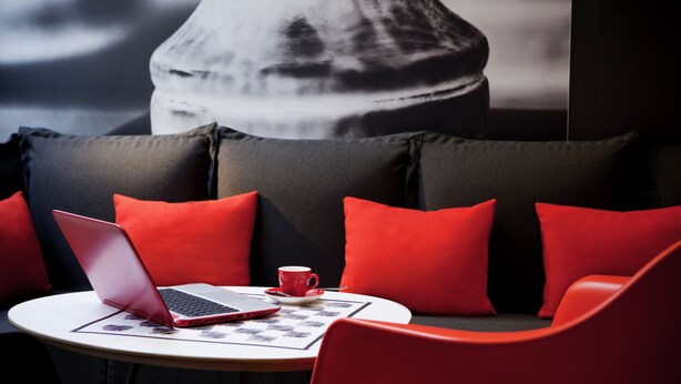 A modern seating area with a laptop, a red cup, and a patterned table mat.