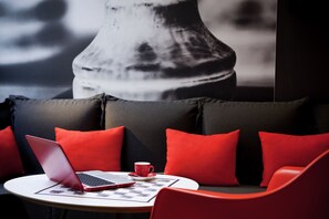 Un área de estar moderna con una laptop, una taza roja y un mantel de mesa estampado.
