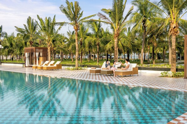 Una piscina al aire libre, sombrillas, sillones reclinables de piscina