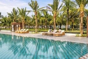 Una piscina al aire libre, sombrillas, sillones reclinables de piscina