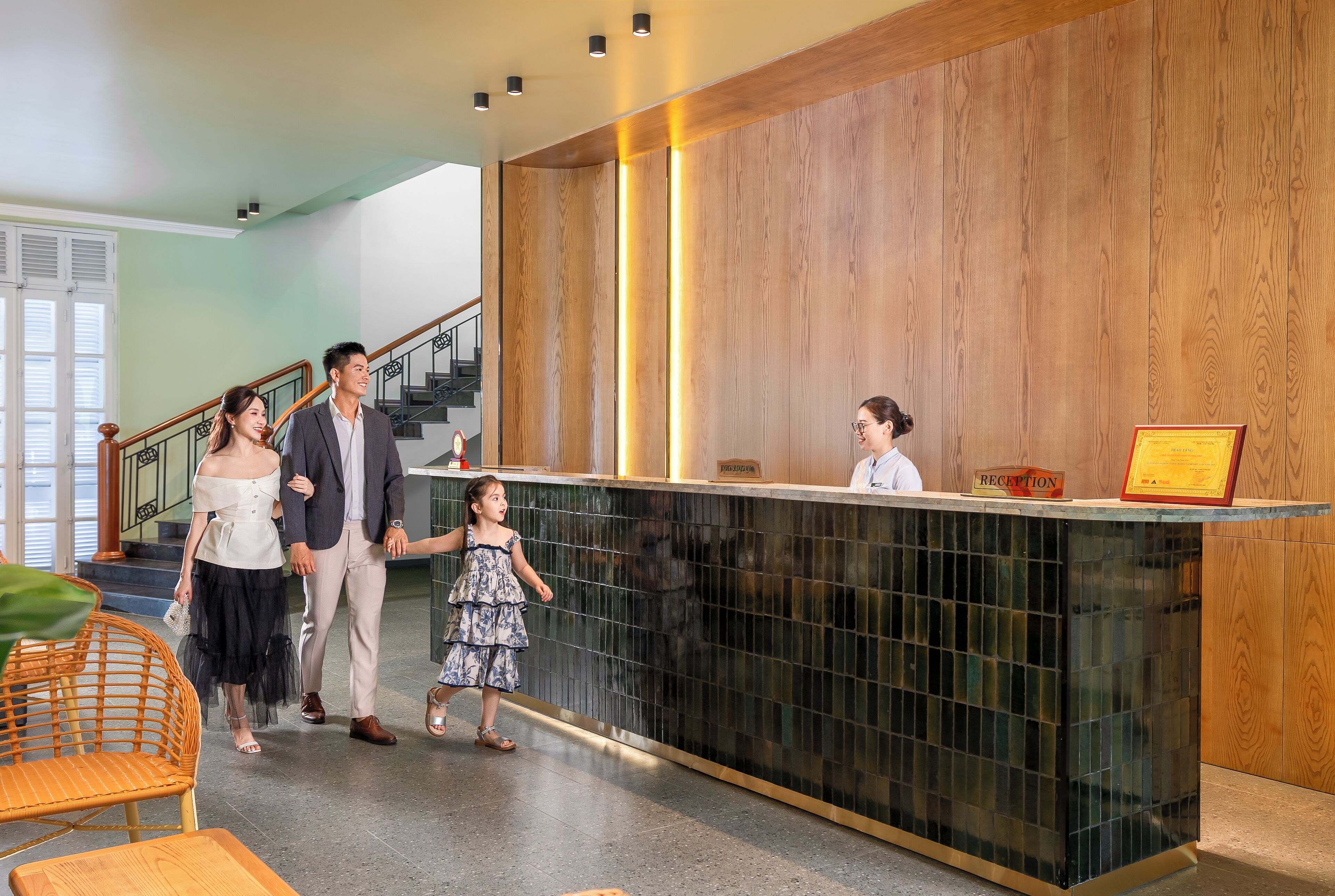 A reception area with a wooden panel wall, a reception desk, and a staircase in the background.