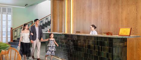 A reception area with a wooden panel wall, a reception desk, and a staircase in the background.