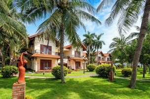 Um resort com vários edifícios de dois andares, palmeiras e gramados bem cuidados.