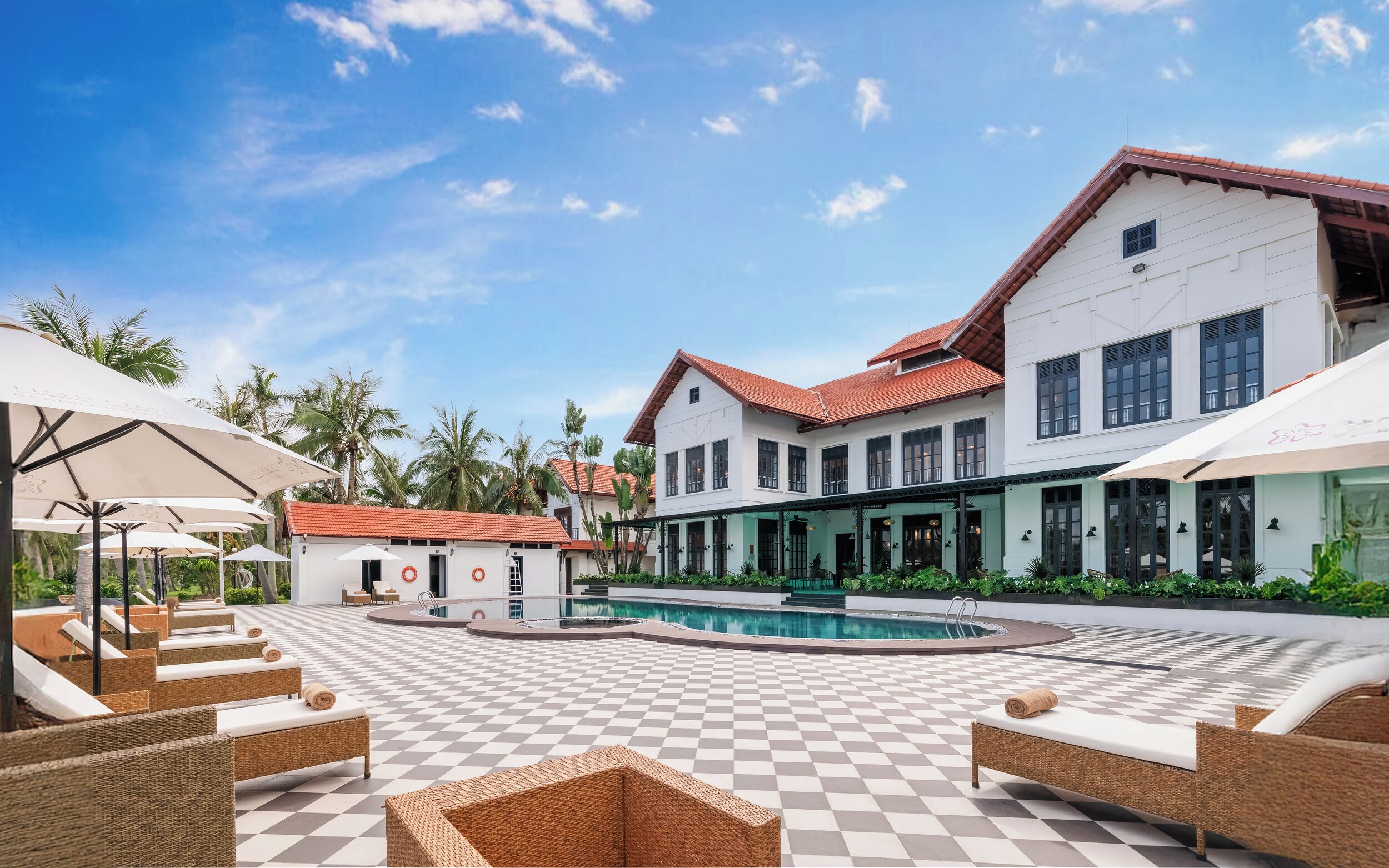 Un resort con piscina, sillas de descanso y un edificio de amplios ventanales.