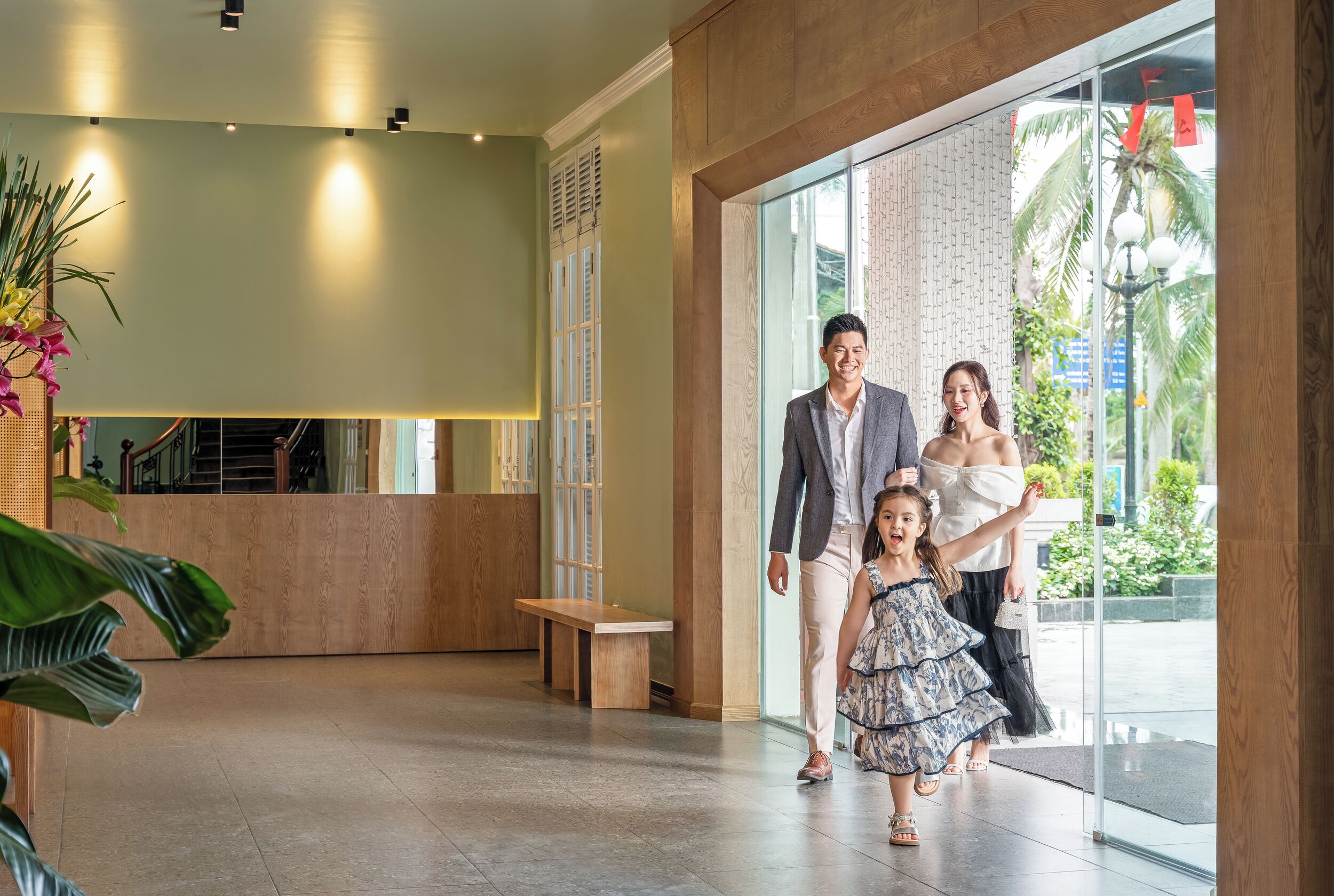 A reception area with a wooden bench, a reception desk, and a large window with a view of palm trees.