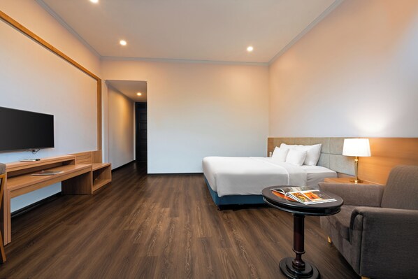 A hotel room with a bed, a desk, a television, a lamp, and a table with a magazine. - Tuan Chau Resort Ha Long (Tuan Chau)