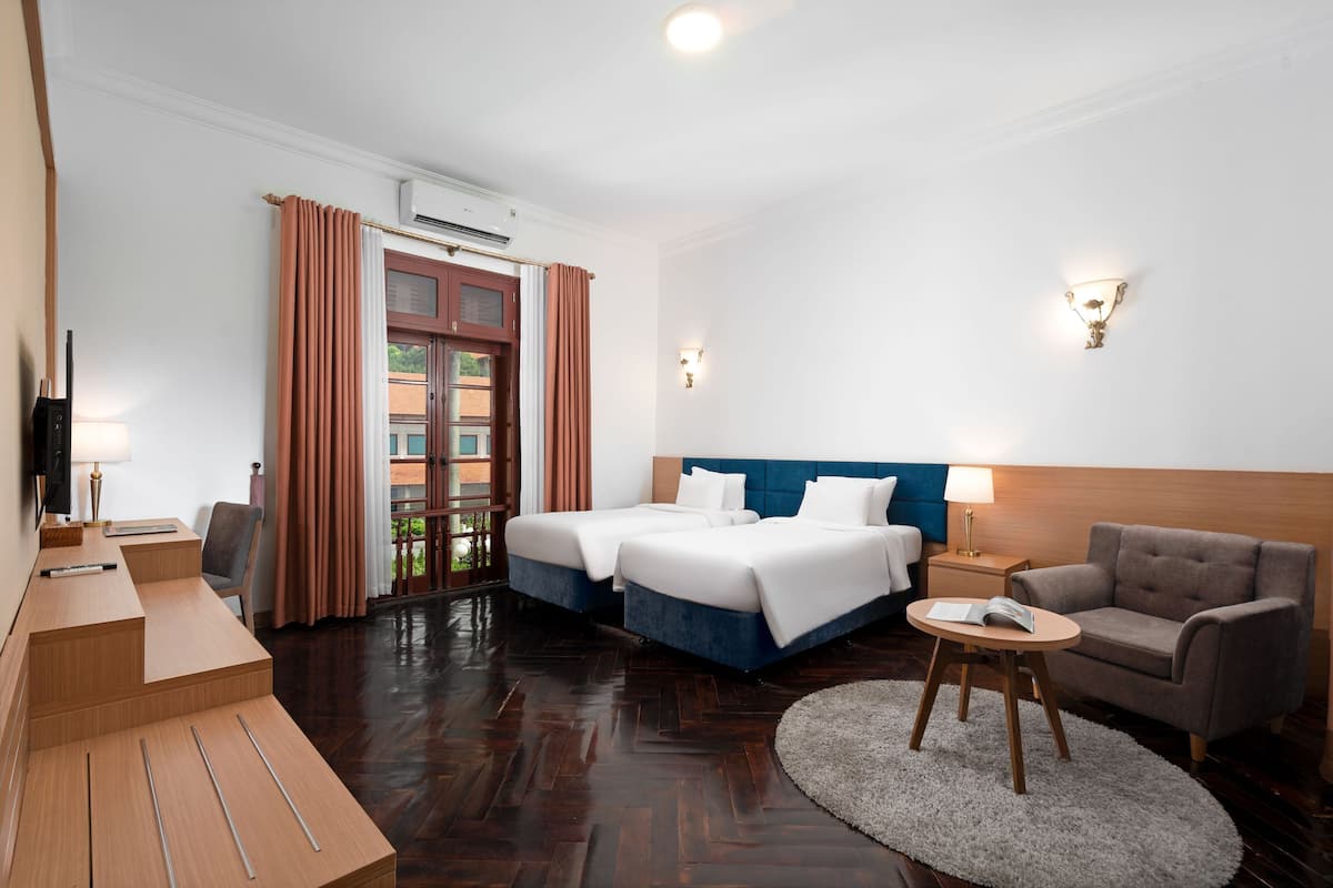 Una habitación de hotel con dos camas, un escritorio, una silla, un sofá y un televisor.