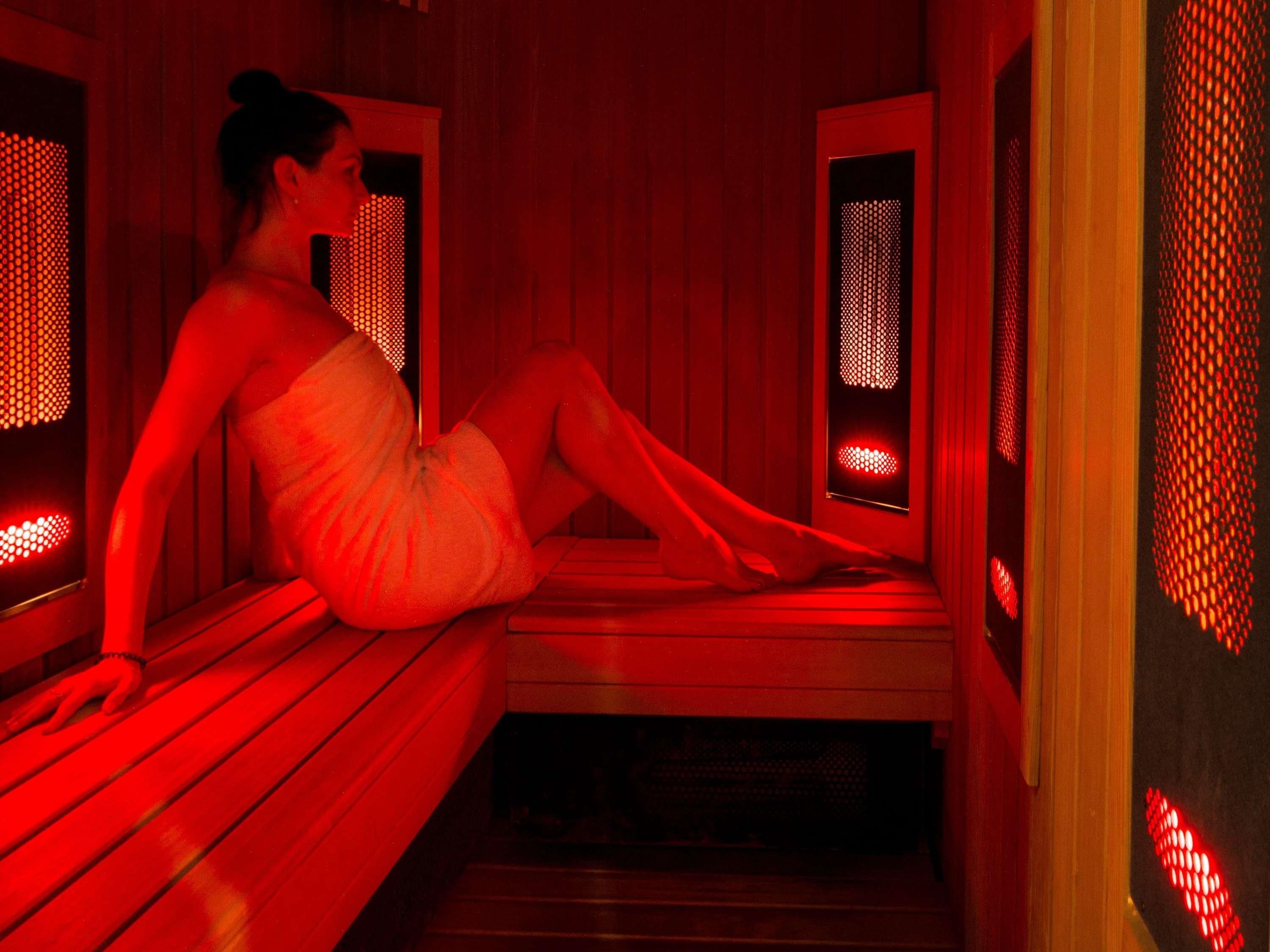 Una sala de sauna con bancos de madera e iluminación roja.