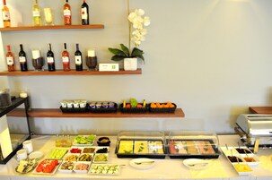 Un bufé con diferentes alimentos y una selección de vinos en estanterías.
