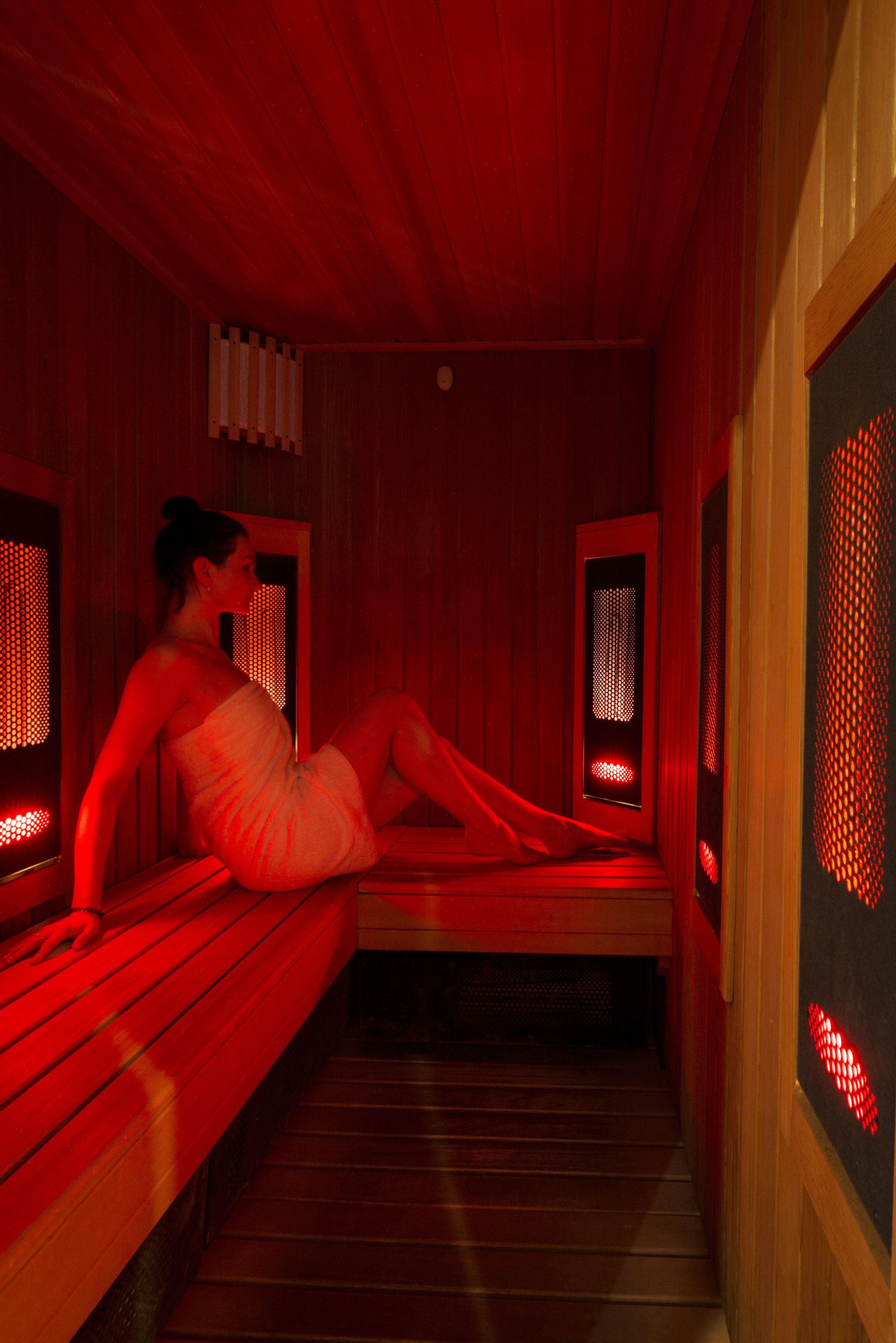 A sauna room with wooden benches and red lighting.