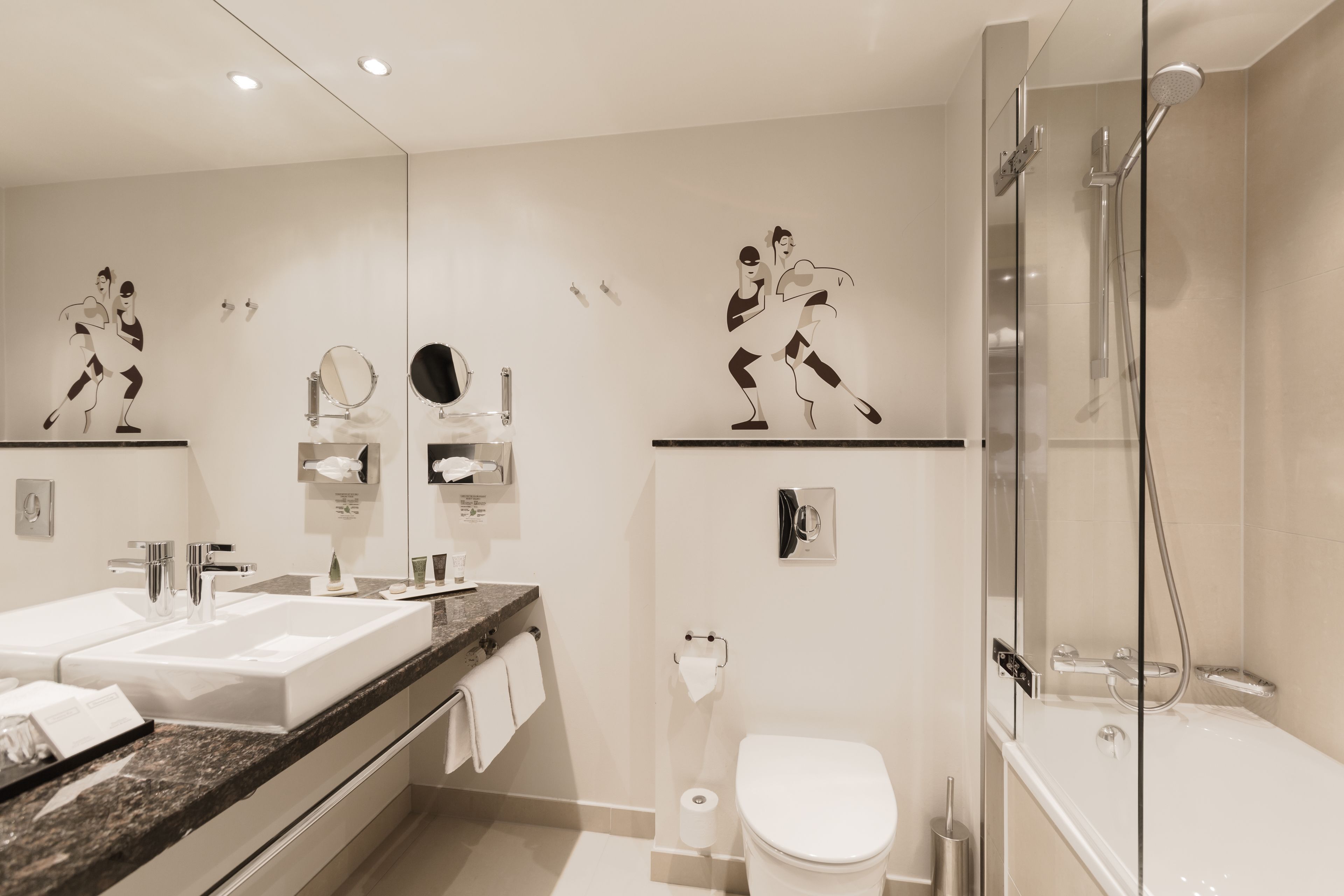 A modern bathroom with dual sinks, a glass-enclosed shower, and decorative wall art.