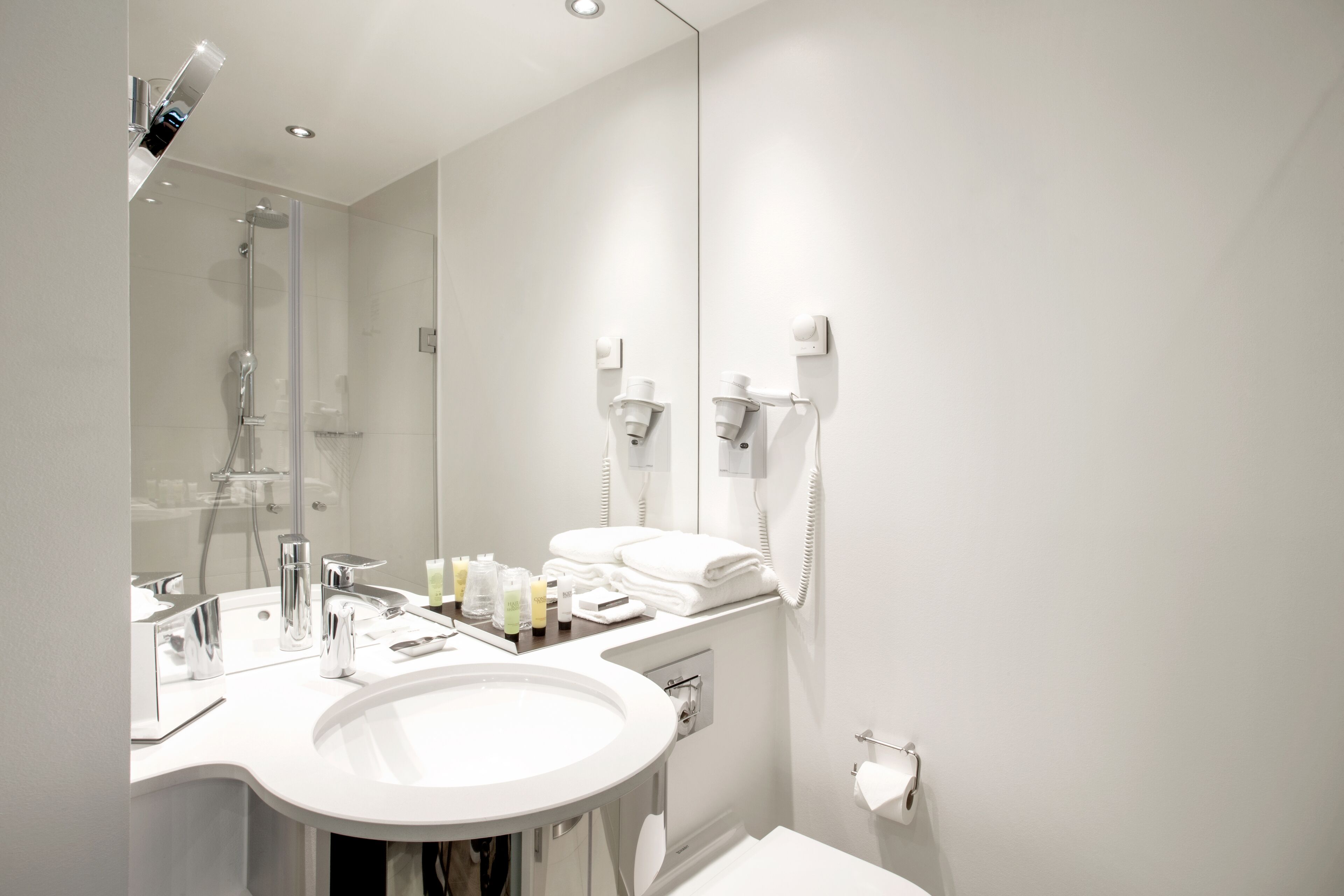 Un baño moderno con un espejo grande, un lavamanos y una ducha.