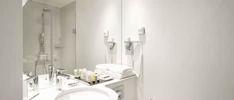 Un baño moderno con un espejo grande, un lavamanos y una ducha.