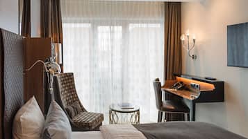 Ein Hotelzimmer mit Bett, Schreibtisch, Stuhl, kleinem Tisch und Lampe.