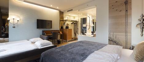 Habitación de hotel con dos camas, un escritorio, una silla, un espejo y un televisor.