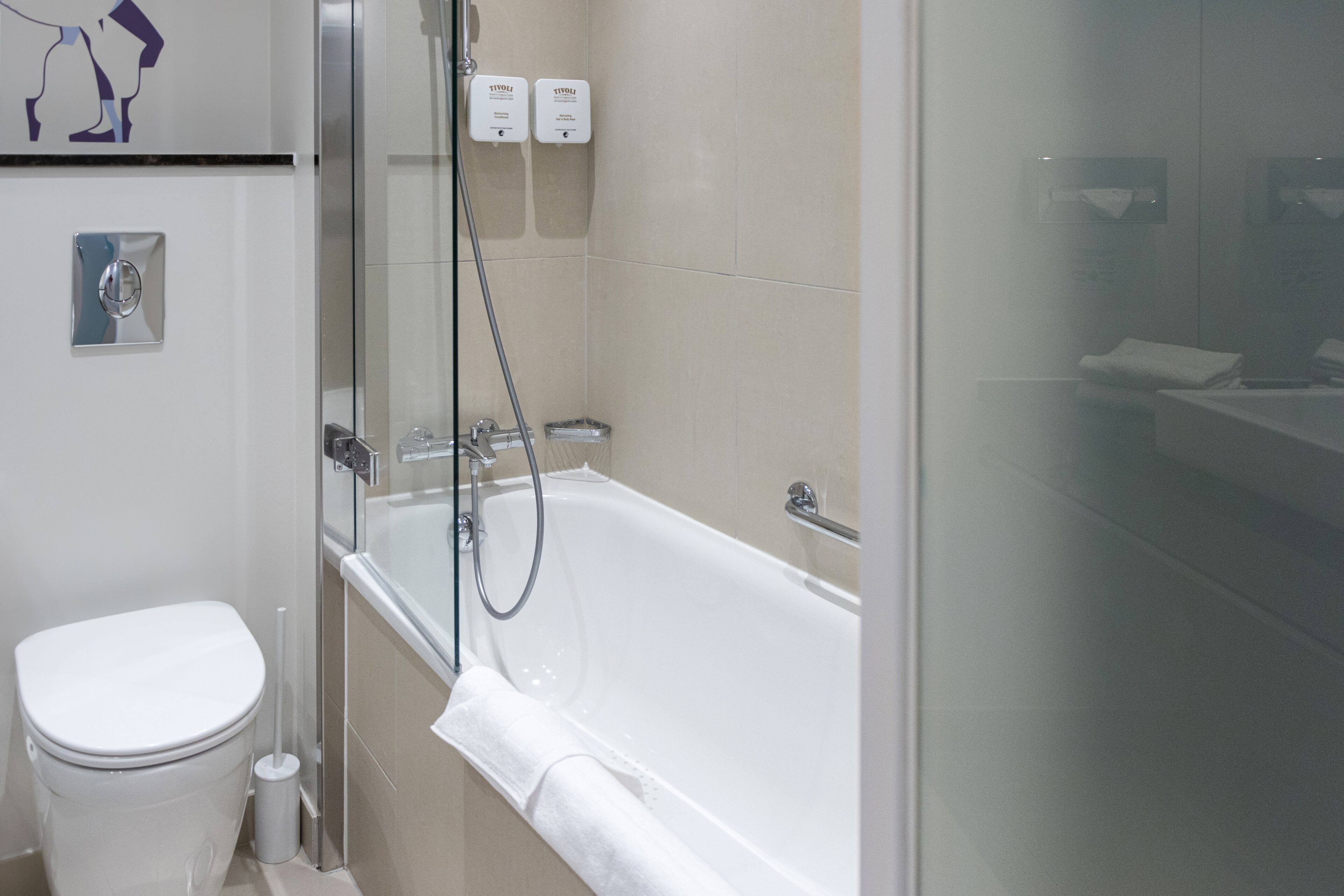 Een moderne badkamer met toilet, een douche met glazen wand en een bad.