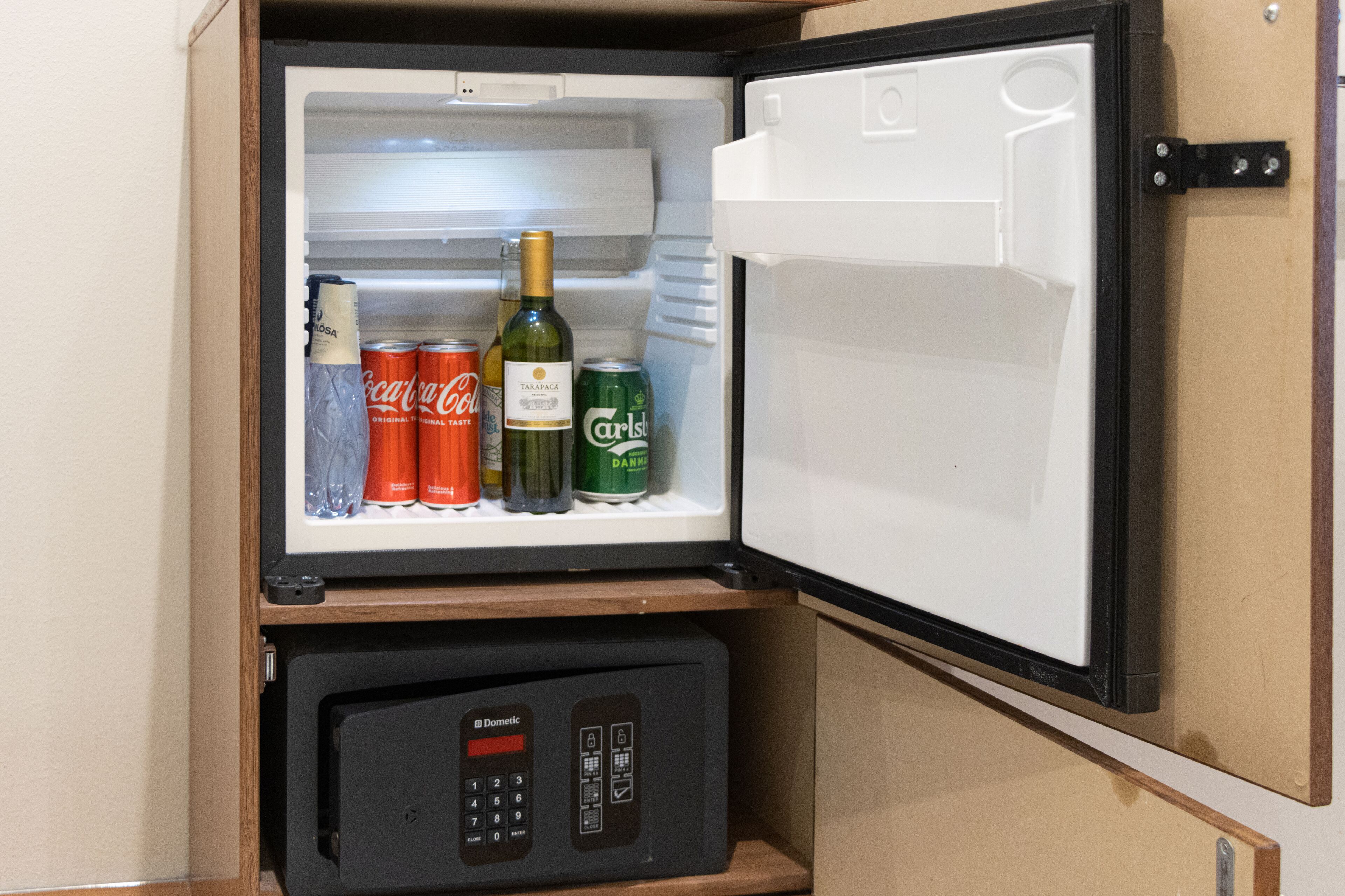 A refrigerator with a freezer compartment, containing beverages and a small appliance.