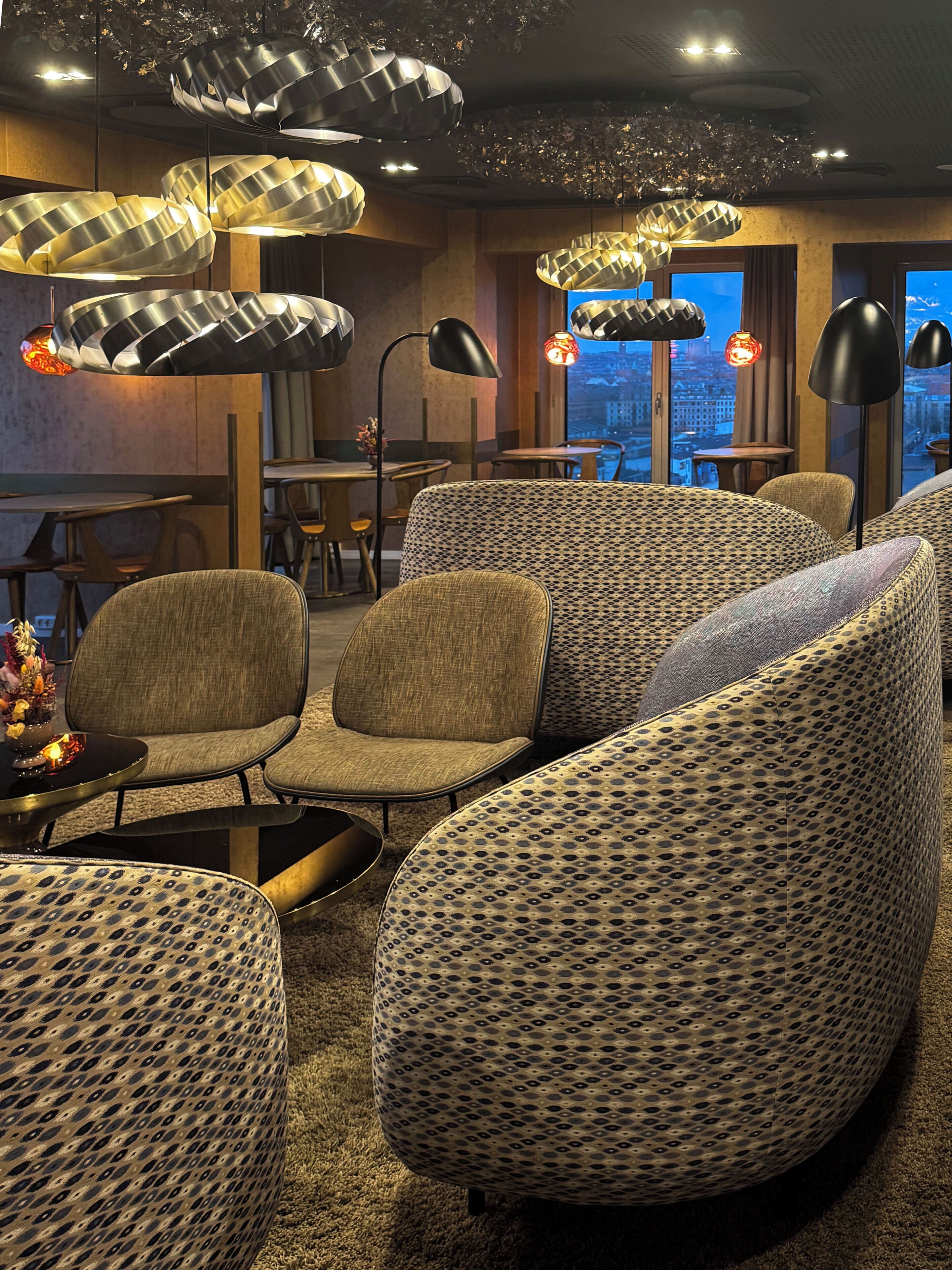 Ein stilvoller Lounge-Bereich mit gemusterten Sofas, einem Couchtisch und Pendelleuchten.