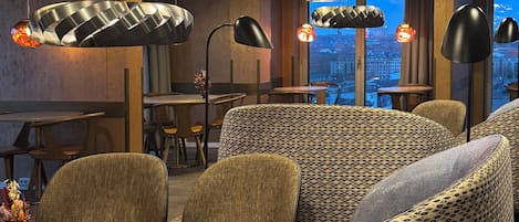 Un área de descanso moderna con sofás estampados, una mesa de centro e iluminación colgante.