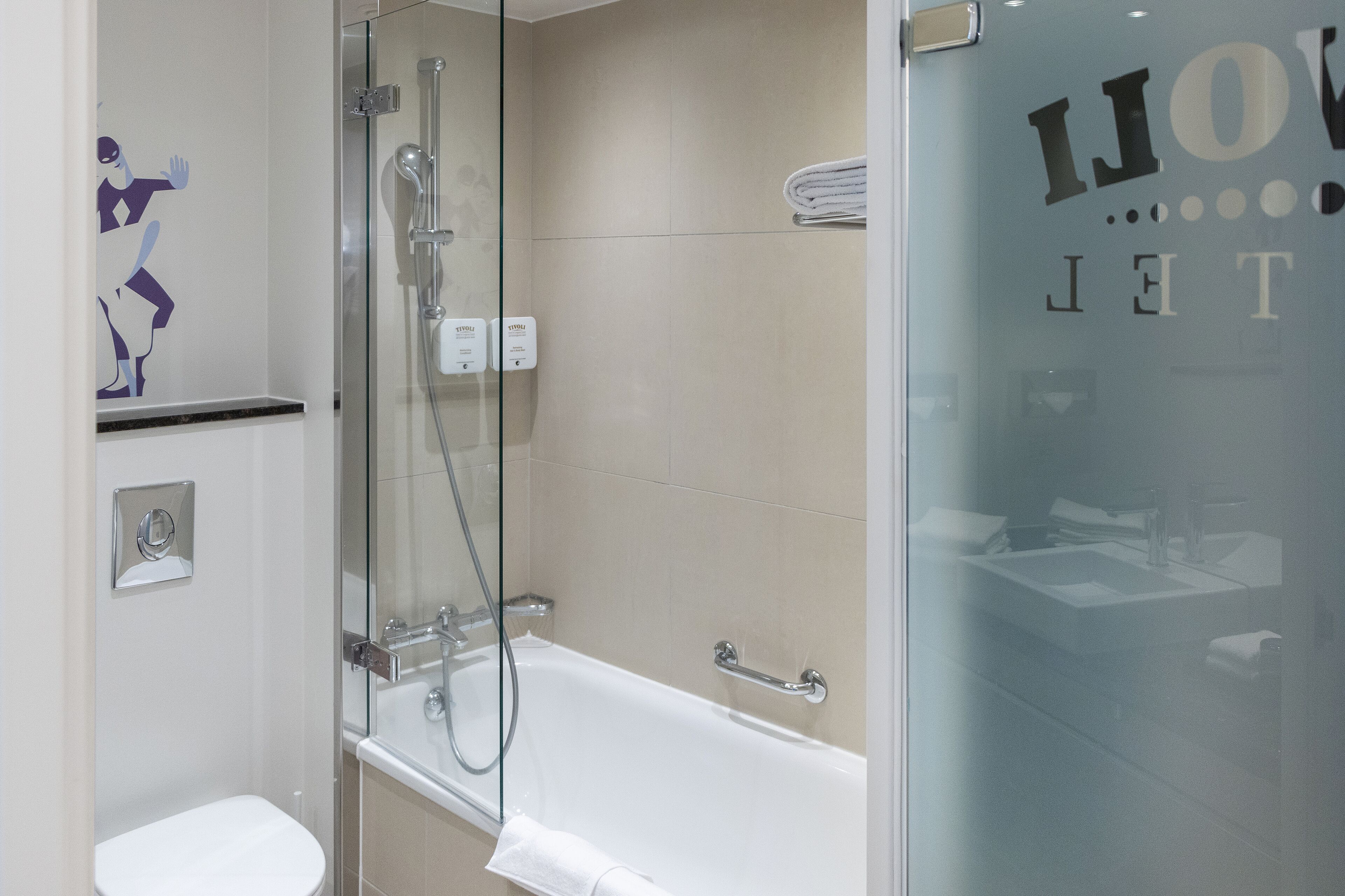A modern bathroom with a glass-enclosed shower, a white bathtub, and a toilet.