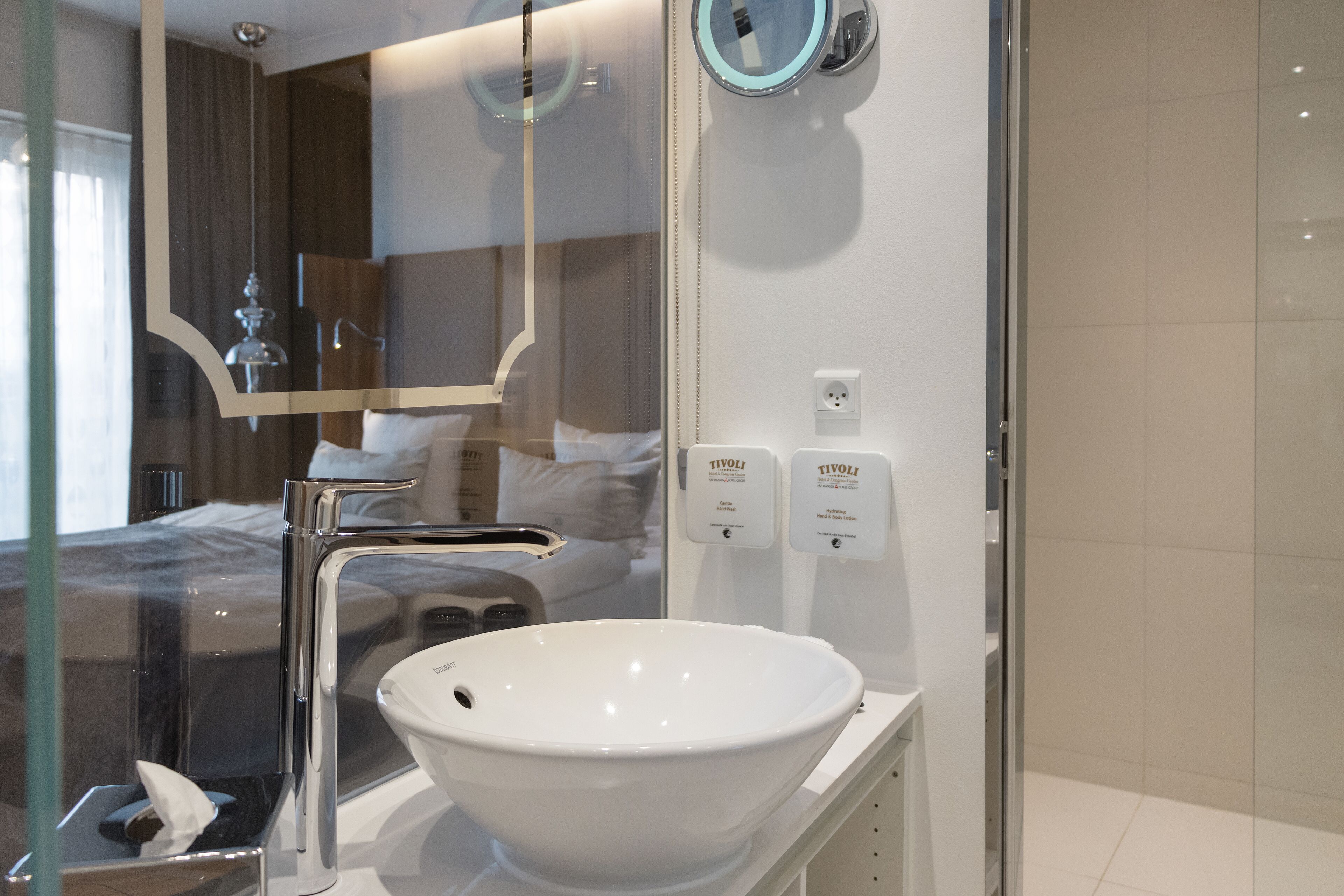 A modern bathroom with a white sink, a glass shower enclosure, and a mirror.