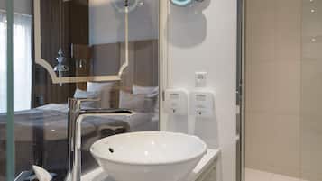 A modern bathroom with a white sink, a glass shower enclosure, and a mirror.