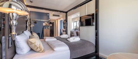 Una habitación de hotel moderna con una cama, un televisor, un escritorio y una lámpara.