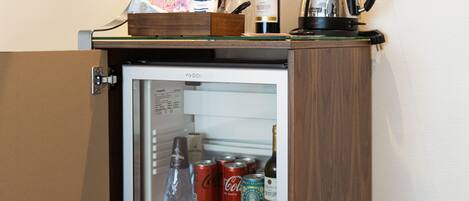 A minibar with a refrigerator containing beverages and a bottle of wine.