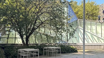 Un patio exterior con una mesa, sillas, un sofá y un árbol grande.