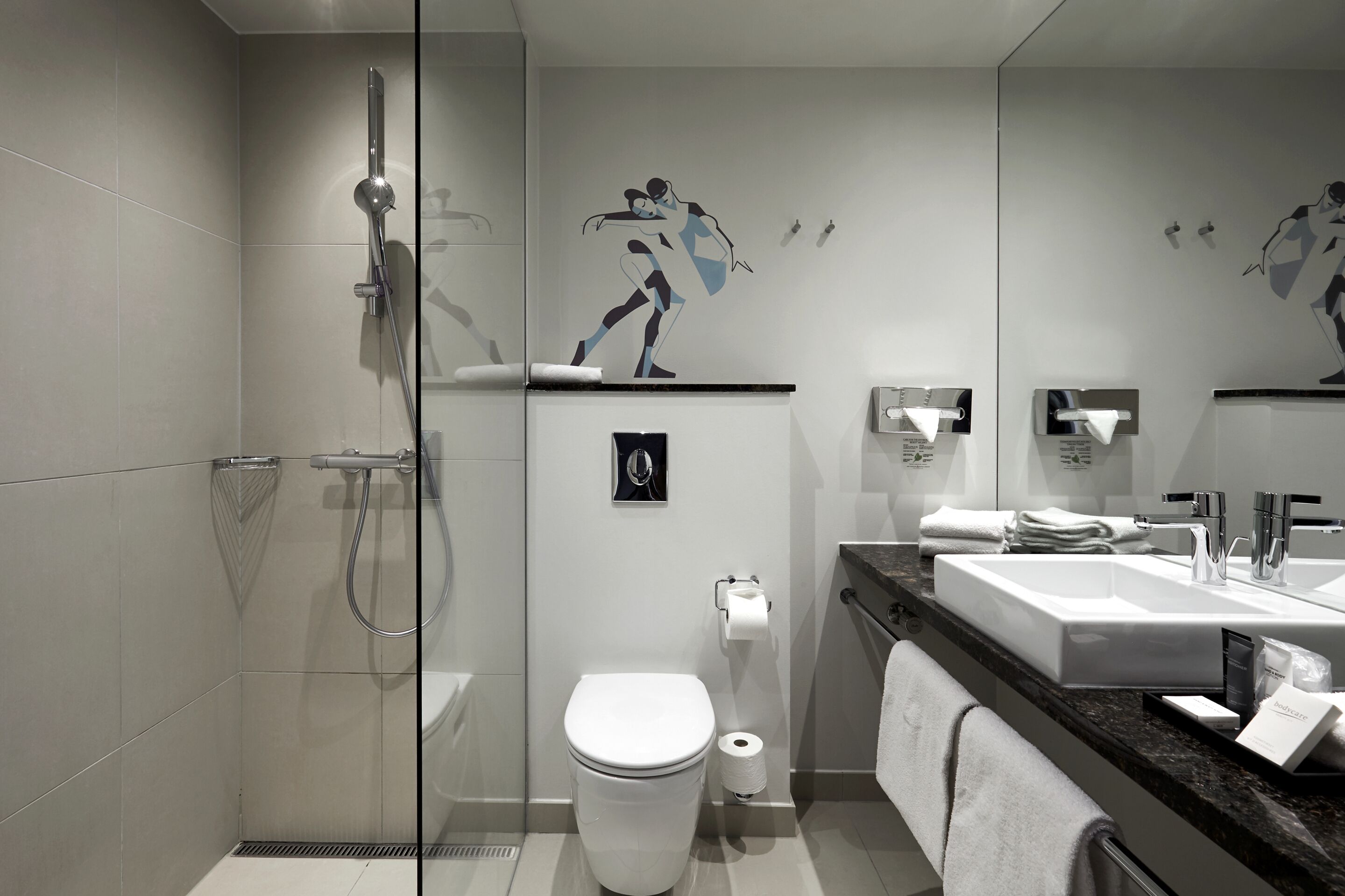 Un baño moderno con ducha de vidrio, inodoro blanco, lavabo con encimera de mármol y un espejo grande.