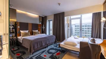 A hotel room with a large bed, a smaller bed, a desk, and a view of the city.