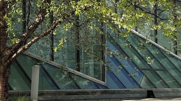 Udendørs siddepladser med et træ og en moderne bygning i baggrunden.