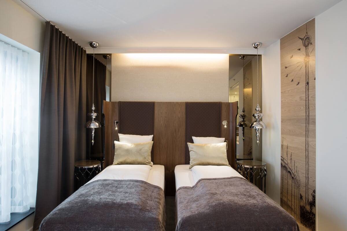 A hotel room with two beds, a large mirror, and a wooden accent wall.