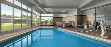 En pool med fri utsikt över omgivningarna, ett soltak och ett område med solstolar.