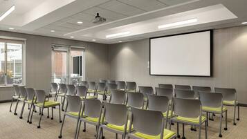 A conference room with rows of chairs, a projector screen, and a large window.