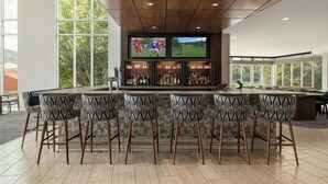 Zona de bar moderna con una barra alargada, varios taburetes y una pantalla de televisión mostrando deportes.