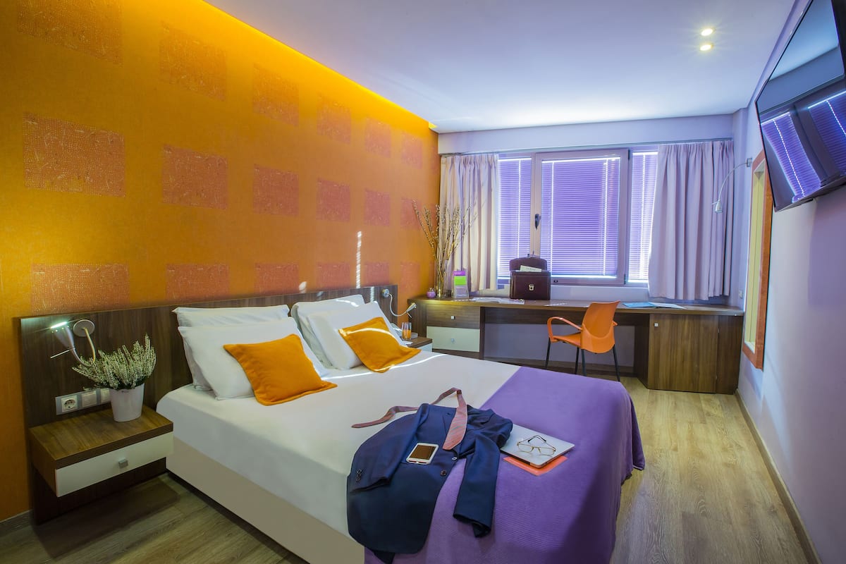 Una habitación de hotel moderna con cama, escritorio y televisión.