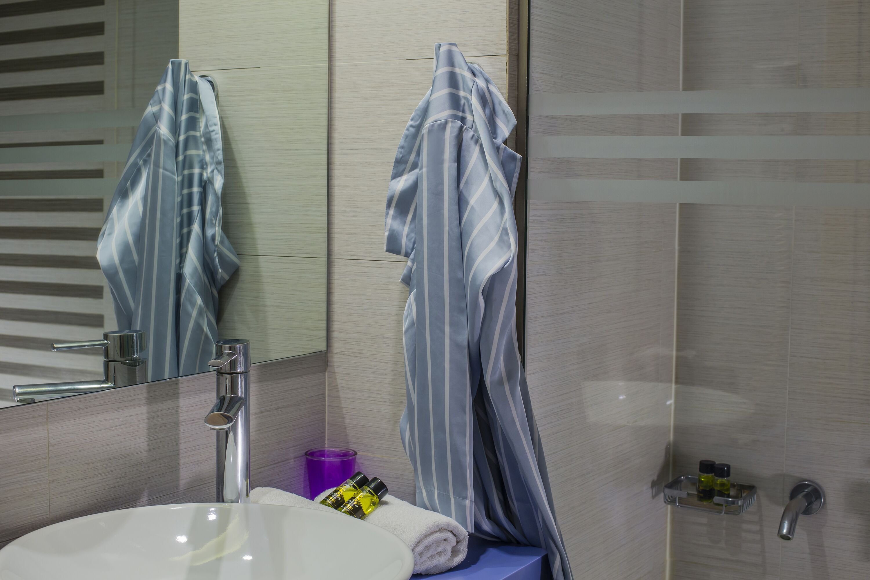 Un bagno moderno con un lavandino bianco, uno specchio e una zona doccia.