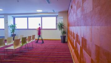 A conference room with a red carpet, multiple chairs, and potted plants.