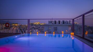 Une piscine sur le toit offrant une vue sur la ville au crépuscule.