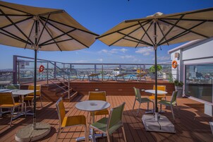 Una terrazza sul tetto con posti a sedere all'aperto, ombrelloni e vista sulla città.