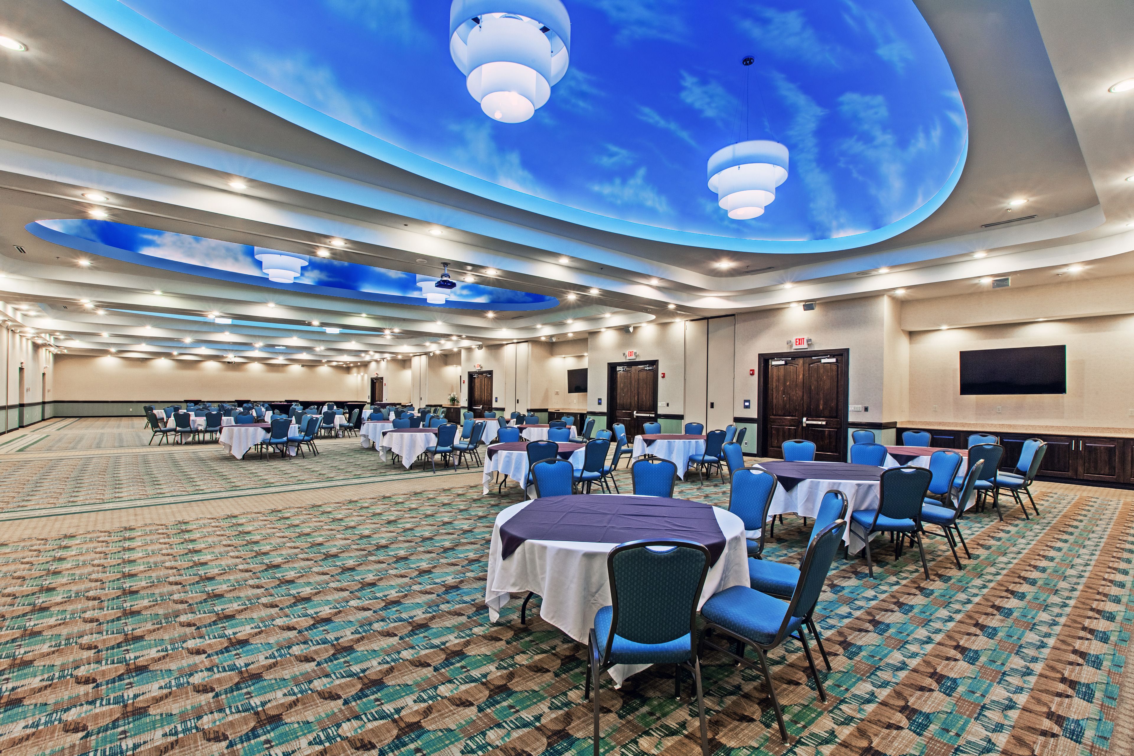 A conference room with round tables, blue chairs, and a patterned carpet.