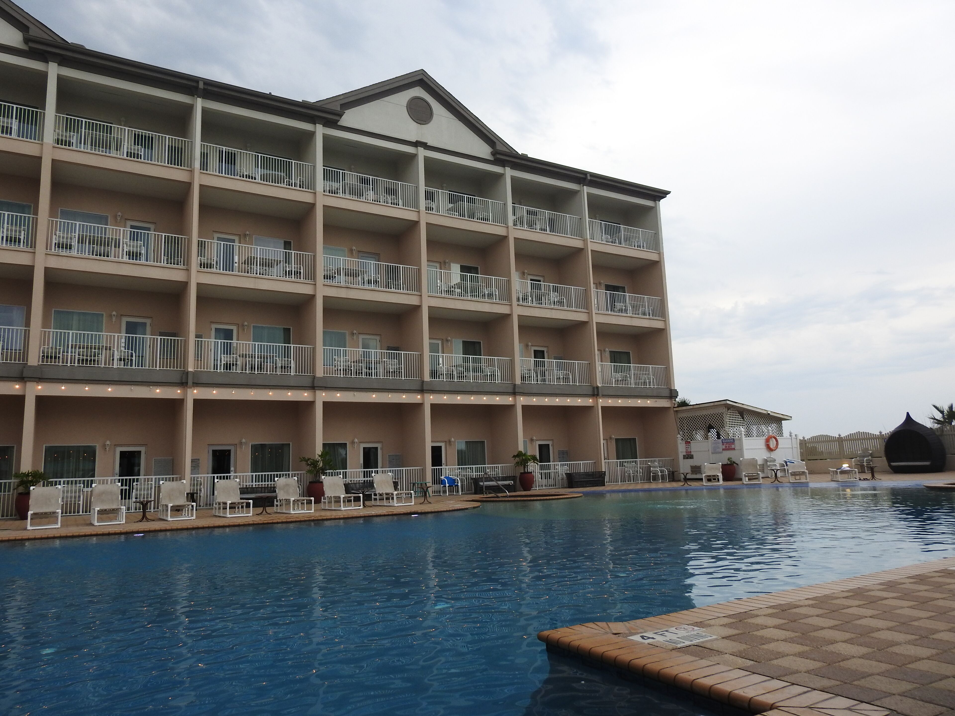 Un hôtel à plusieurs étages doté d’une piscine, de balcons et d’un espace extérieur aménag é pour s’asseoir.